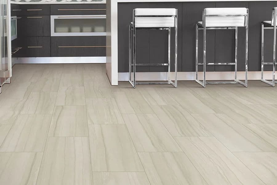 Modern kitchen with light gray tile flooring and sleek bar stools at a stylish counter.