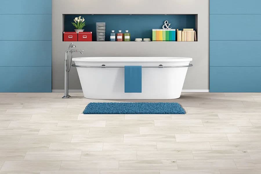 Modern bathroom with a freestanding tub, blue rug, and stylish wall shelves.