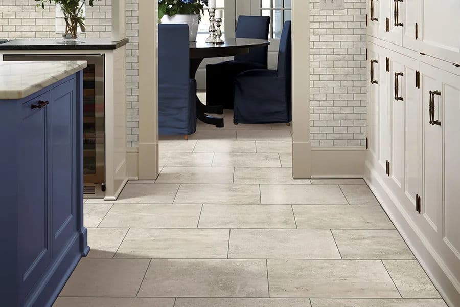 Modern kitchen interior featuring gray tile flooring, blue cabinetry, and white cabinets.