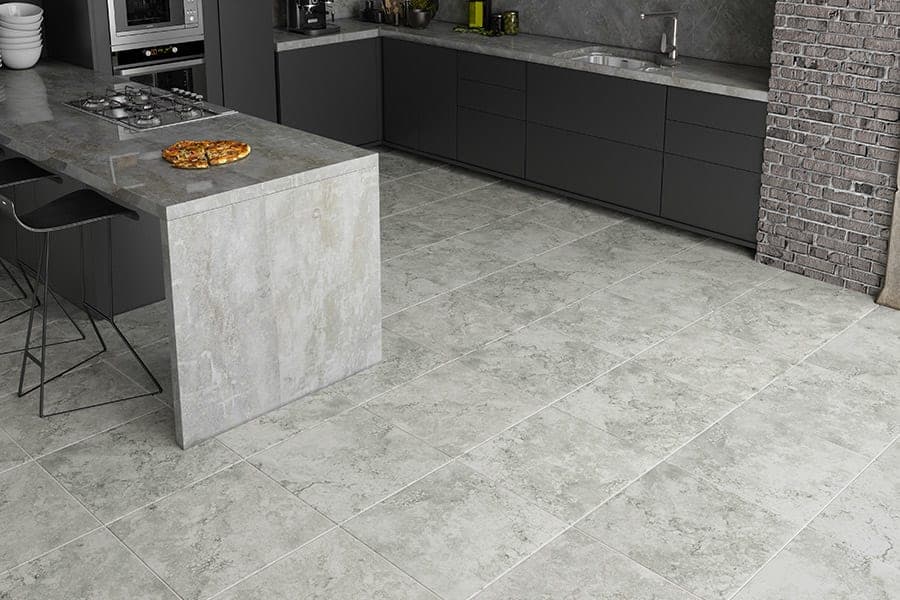 Modern kitchen featuring gray stone tiles, sleek cabinets, and a stylish island with bar stools.