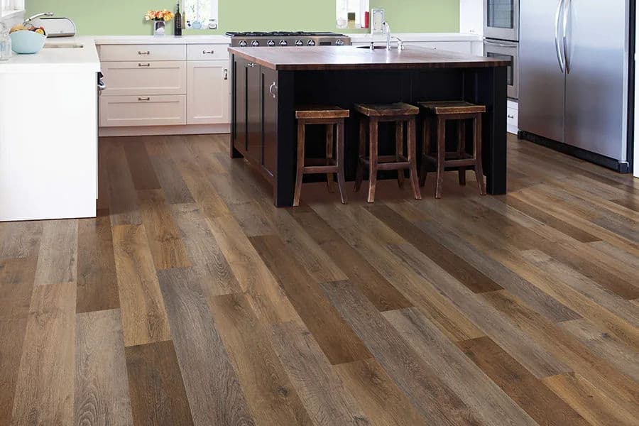Modern kitchen with wooden floor, island, and bar stools, showcasing stylish interior design.