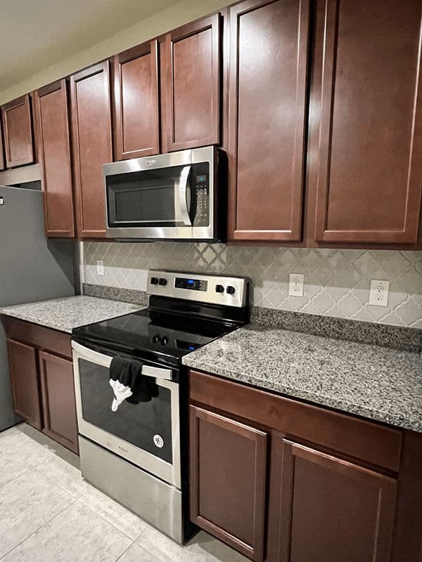 Modern kitchen featuring stainless steel appliances, dark wood cabinets, and granite countertops.