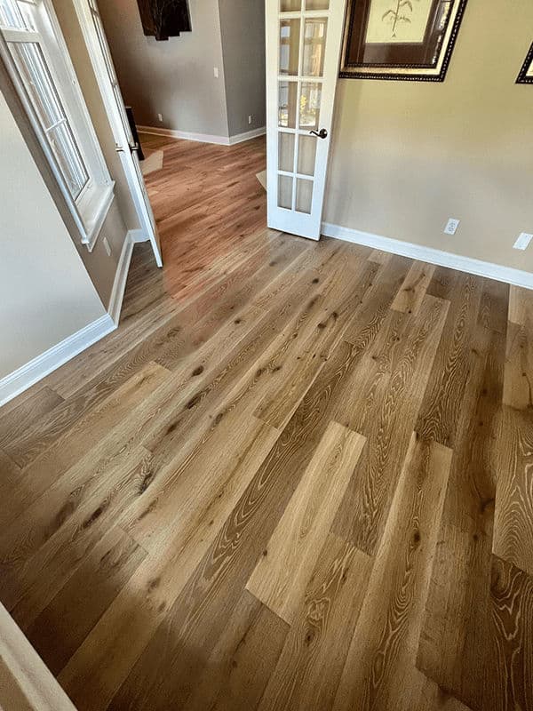 Modern wood flooring in a bright interior space with open doorway and elegant design.