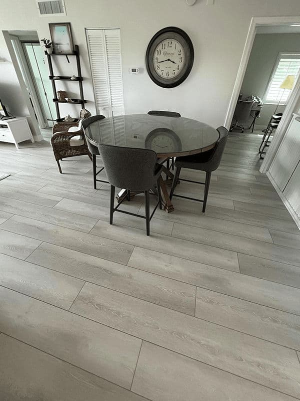 Modern dining area with round glass table, four chairs, and light wood flooring.