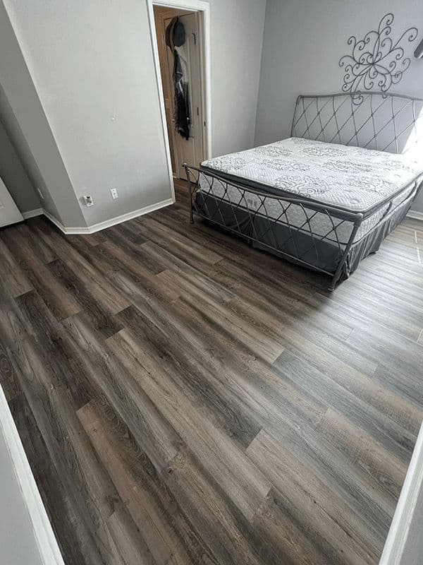 Modern bedroom featuring a stylish bed, gray walls, and dark wood flooring.