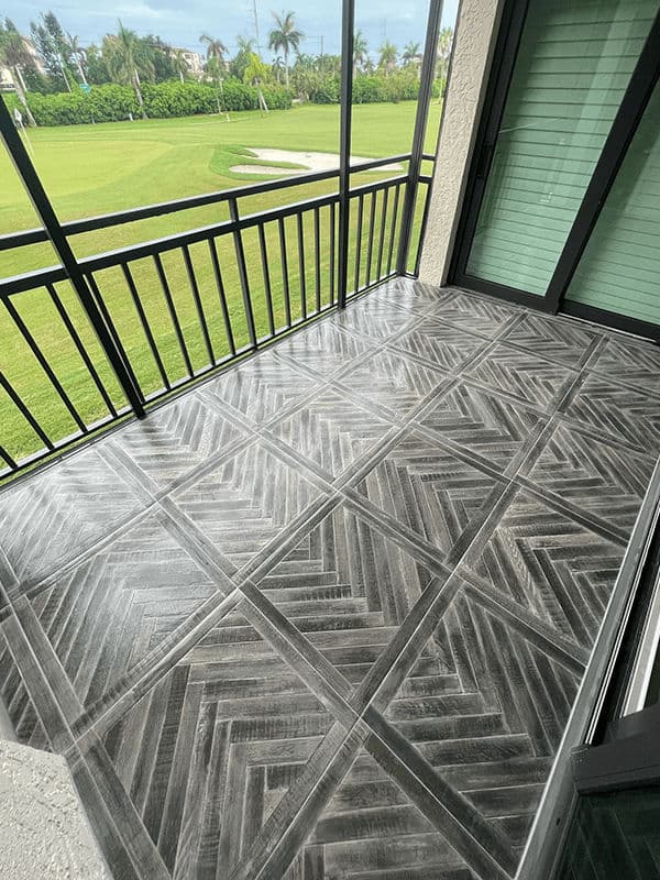 Herringbone patterned tile flooring on a balcony with green landscape view.