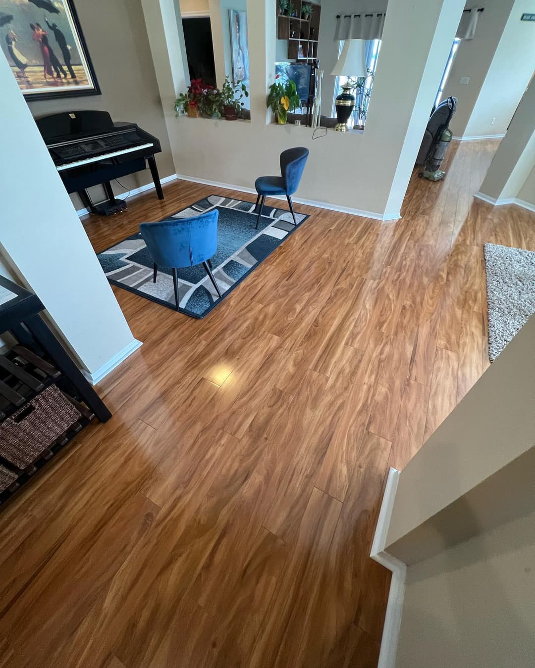 Modern living room with polished wood floors, piano, and stylish seating area.