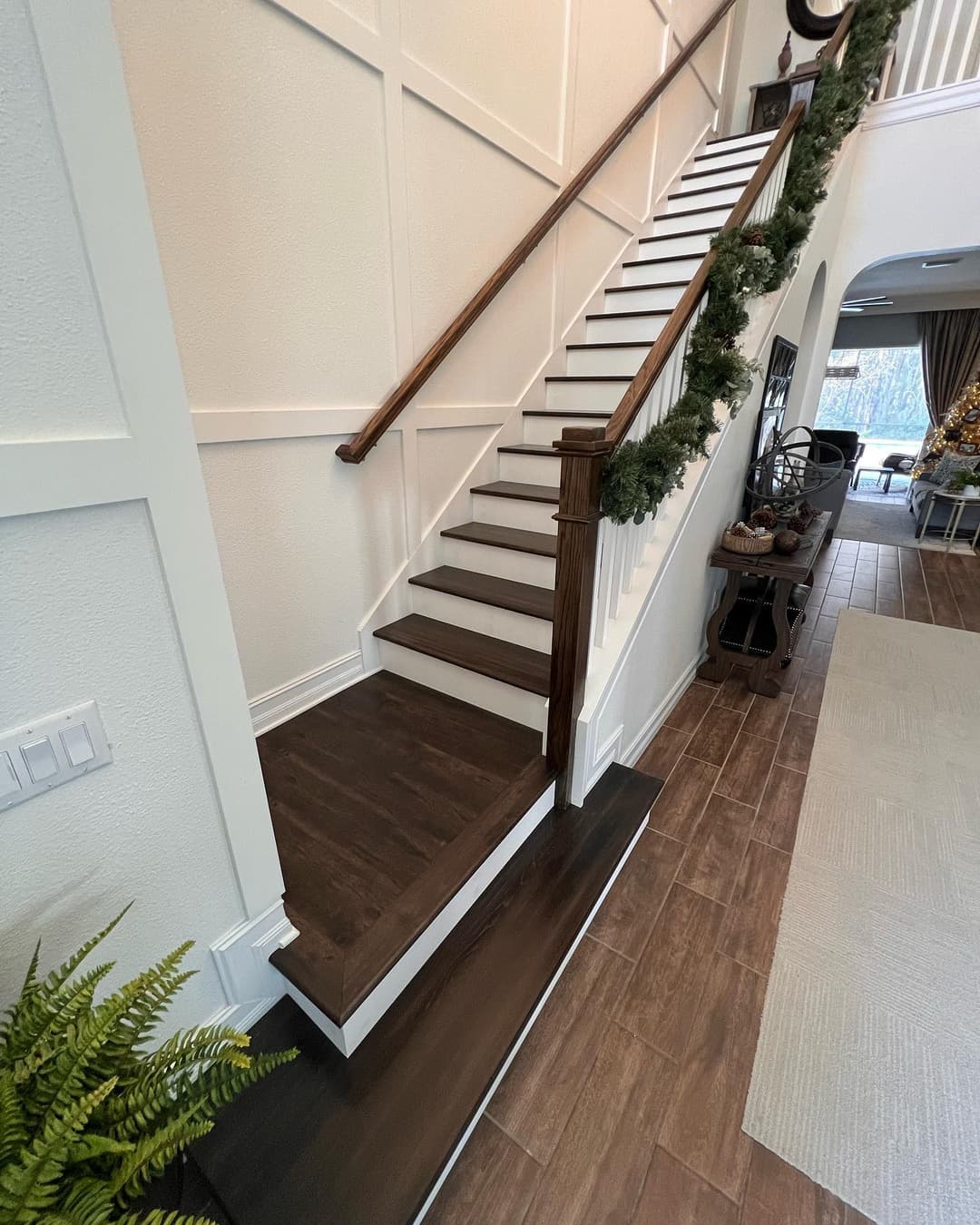 Interior staircase with wooden steps and decorative railing in a bright hallway.