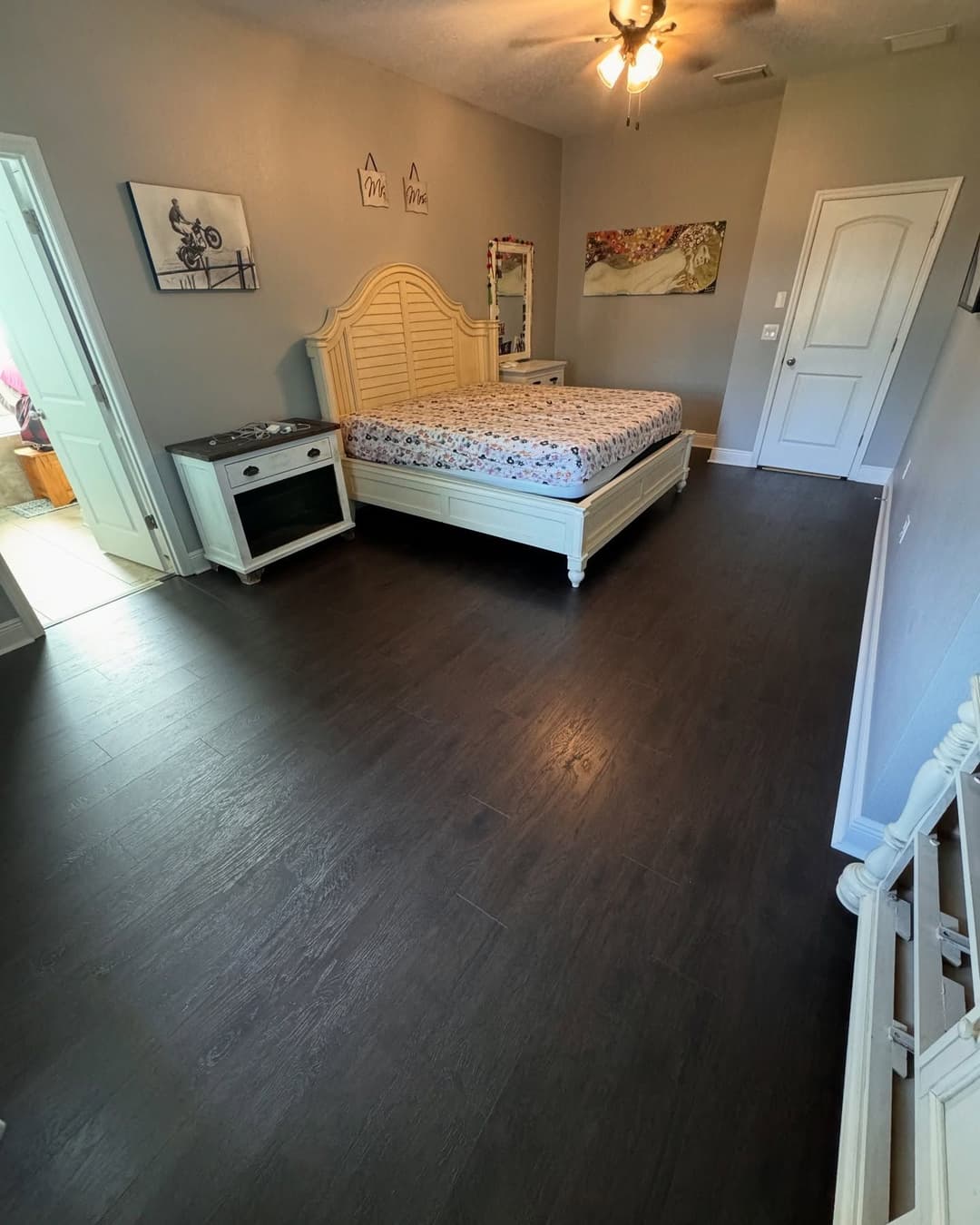 Spacious bedroom featuring a white bed, dark hardwood floor, and modern decor.